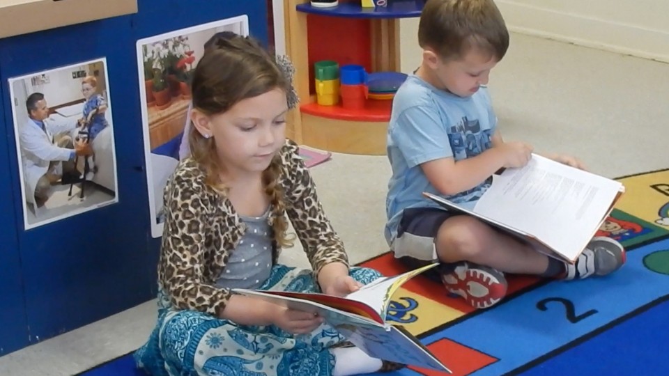 Two children reading books in a classroom