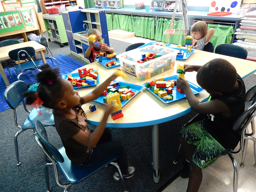 Four children at a table playing with building blocks