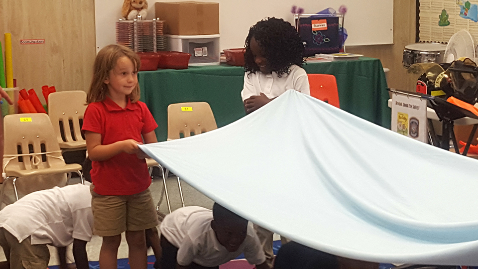 Children in a classroom building a tent