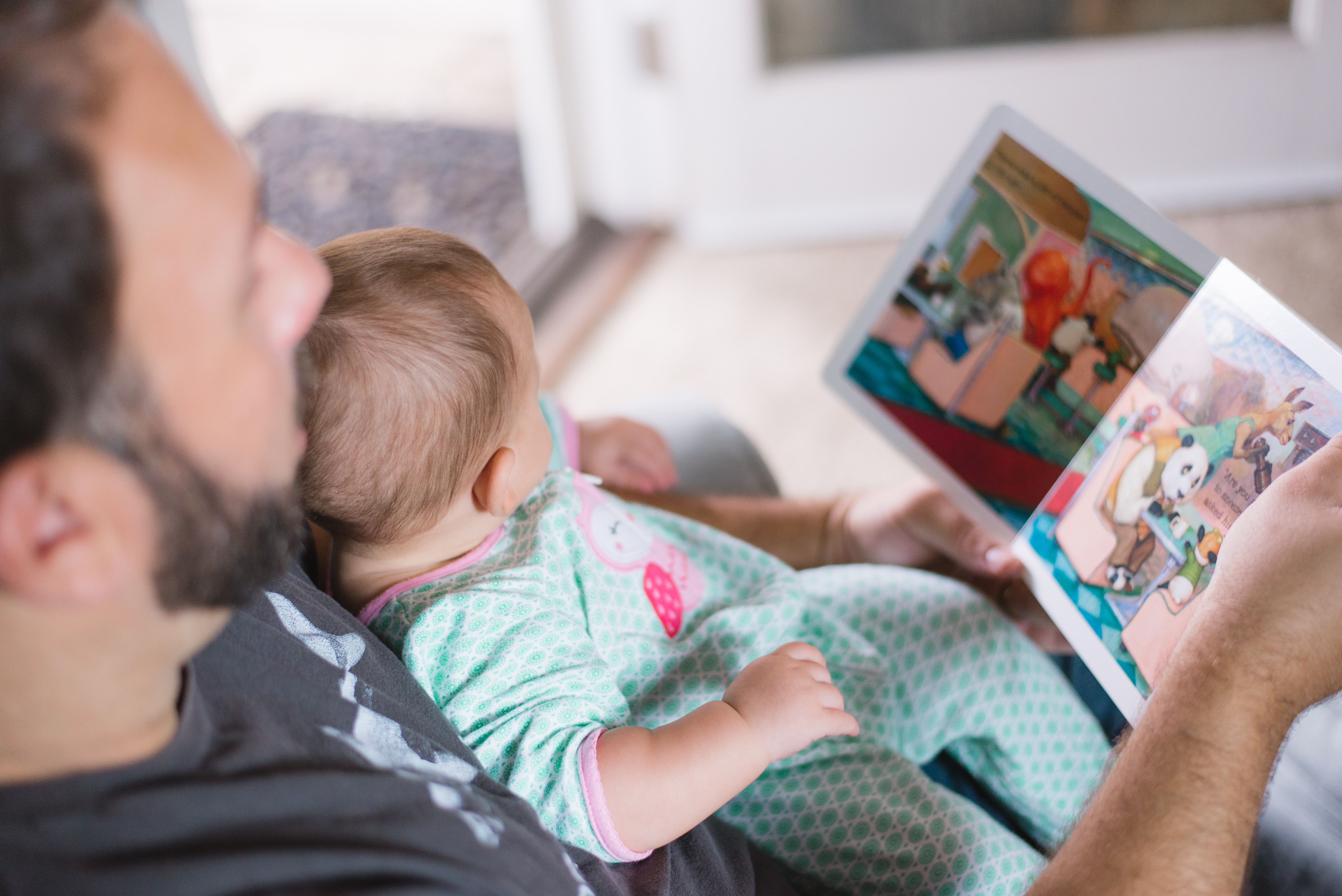 A father reading to his baby is another step in  building the baby's brain and preparing him for kindergarten